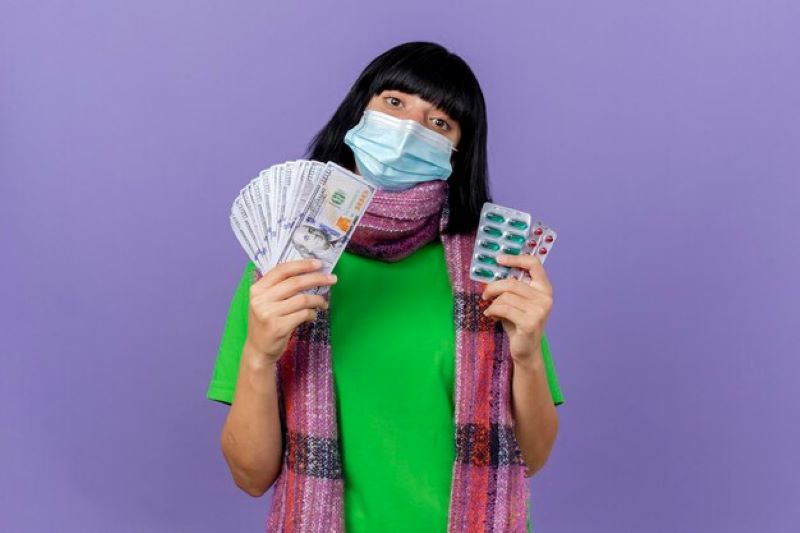 young ill woman wearing mask scarf holding money packs capsules looking front isolated purple wall with copy space 141793 85527